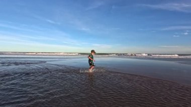 Okyanusun kıyısındaki bir huş ağacında kumda gömülü bir çocuk.,