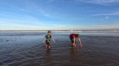 Okyanusun kıyısındaki bir huş ağacında kumda gömülü bir çocuk.,