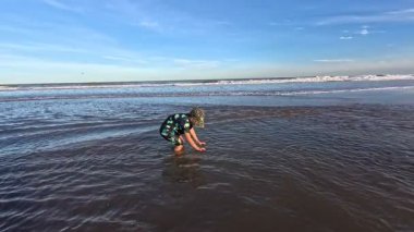 Okyanusun kıyısındaki bir huş ağacında kumda gömülü bir çocuk.,
