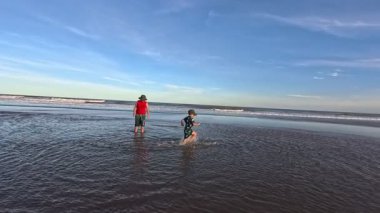 Okyanusun kıyısındaki bir huş ağacında kumda gömülü bir çocuk.,