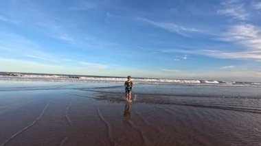 Okyanusun kıyısındaki bir huş ağacında kumda gömülü bir çocuk.,