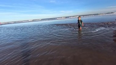 Okyanusun kıyısındaki bir huş ağacında kumda gömülü bir çocuk.,