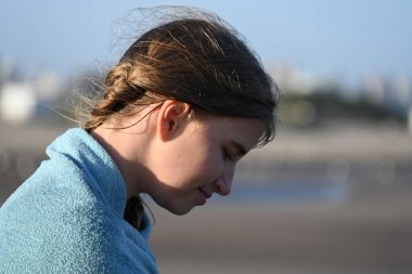 Sarışın bir kız, okyanusun kenarındaki huş ağacına sarılmış.,