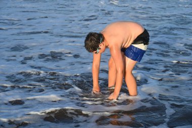 Okyanus kenarında güneş gözlüğü takan adam.