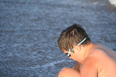 Okyanus kenarında güneş gözlüğü takan adam.