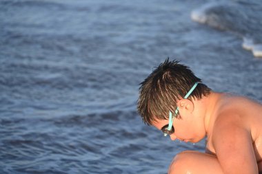 Okyanus kenarında güneş gözlüğü takan adam.