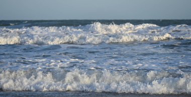 Dalgalar açık gökyüzünün altında kıyıya çarpıyor