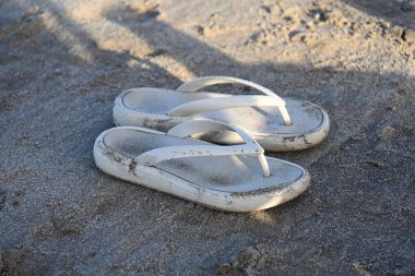 Kumlu sahil yüzeyinde beyaz terlikler vardı.