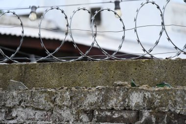 Beton duvarı çevreleyen dikenli teller.