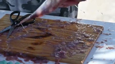 Balıklar masada bıçak ve balık makasıyla temizleniyor.,