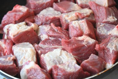 Tavada çiğ et parçaları.