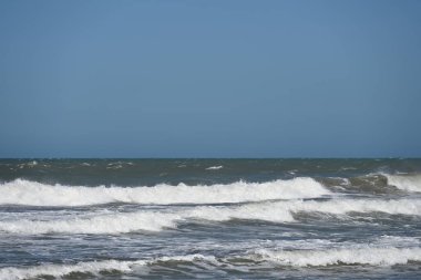 Dalgalar açık gökyüzünün altında kıyıya çarpıyor