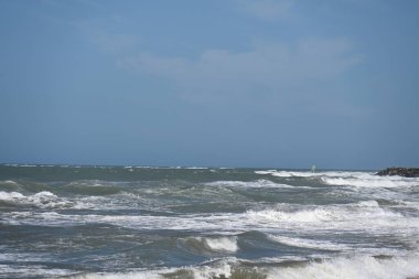 Dalgalar bulutların altında kayalık kıyılara çarpıyor.