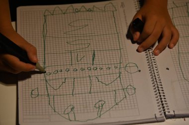 Kağıt üzerinde kalemle ev çizen çocuk.