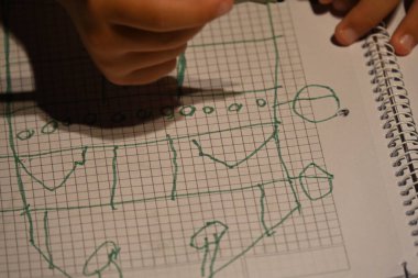 Çocuk dizüstü bilgisayara ızgara tabanlı bir tasarım çiziyor.