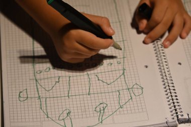 Çocuk dizüstü bilgisayara ızgara tabanlı bir tasarım çiziyor.