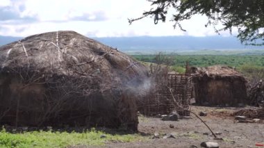 Natron Gölü yakınlarındaki Engare Sero bölgesindeki geleneksel Maasai Clay Yuvarlak Kulübesinden ve Afrika 'daki Tanzanya' daki Ol Doinyo Lengai volkanından duman sızıyor.