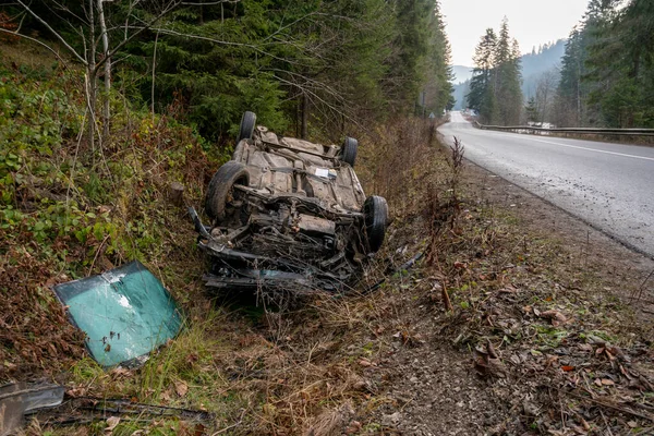 Auto narazilo na nehodu na horské cestě a spadlo vzhůru nohama. Modré auto se převrátilo v příkopu u dálnice — Stock fotografie