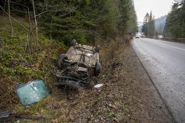 Auto narazilo na nehodu na horské cestě a spadlo vzhůru nohama. Modré auto se převrátilo v příkopu u dálnice — Stock fotografie