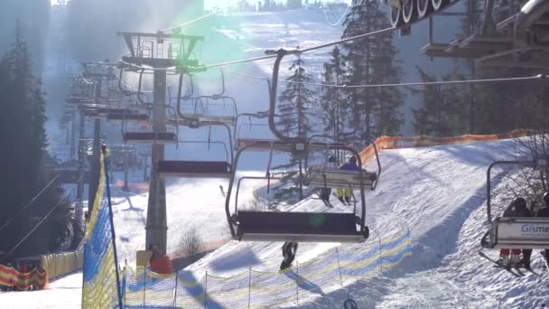 BUKOVEL, UKRAINE - DECEMBER 2020: Skiers on the Chair Lift Moving on the Mountain Top At Sunny Day in Bukovel Ski Resort, Carpathians, Ukraine — стокове відео