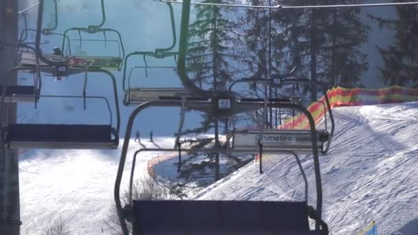 BUKOVEL, UCRANIA - DICIEMBRE 2020: Esquiadores en el telesilla en movimiento en la cima de la montaña En el soleado día en la estación de esquí de Bukovel, Cárpatos, Ucrania — Vídeo de stock