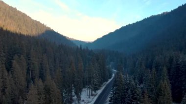 Güzel kış havası manzarası. Tepedeki Dağlar 'daki bir nehirle karlar firavun ağaçlarını ve yolları kapladı. Kış ormanı ve yol yukarıdan