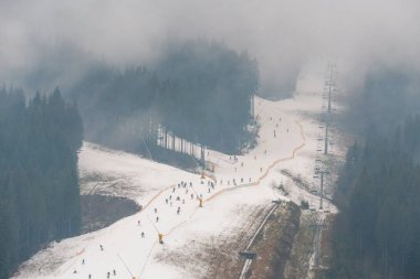 Sis Havacılık Manzarası 'nda kayak yapmak. Bukovel 'deki Misty Low Season, Ukrayna Karpatya Dağlarındaki en büyük kayak merkezi. Ilık Sonbahar Havasında İnsan Yapımı Karla kaplı yamaçlar