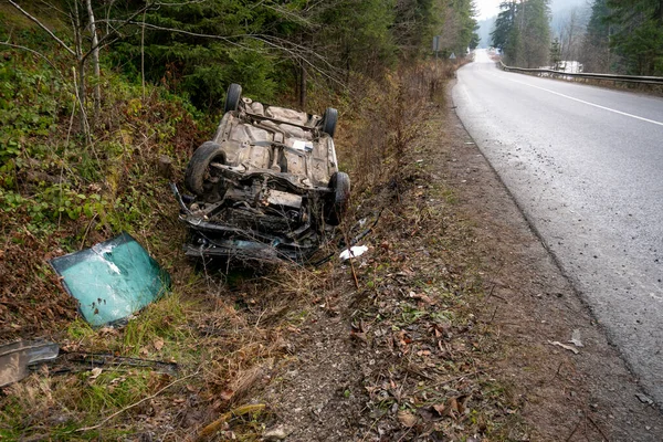 Auto narazilo na nehodu na horské cestě a spadlo vzhůru nohama. Modré auto se převrátilo v příkopu u dálnice — Stock fotografie