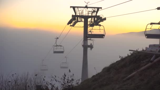 Sedia Ascensore Spostarsi sulla cima della montagna chiara Al tramonto Escalation dalla nebbia. Foggy Day nella località sciistica di Bukovel, Carpazi, Ucraina — Video Stock
