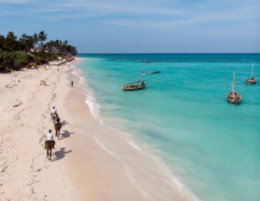 Nungwi sahilindeki sahil şeridinde yürüyen atlı uçakların görüntüsü. Geleneksel Afrika Tahta Dhow Dhow Tekneleri Zanzibar kıyısı yakınlarındaki Temiz Turkuaz Suyu 'nda