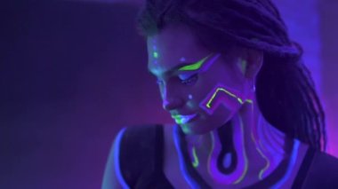 Neon UF Light 'ta Dreadlock' lu bir kızın portresi. Flüoresan Yaratıcı Psikedelik Makyajlı Model Kız, UV 'deki Kadın Disko Dansçısı Modeli, Renkli Soyut Makyaj. Dans eden bayan.