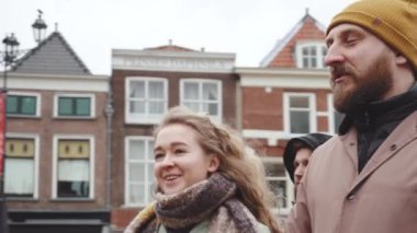 Yakışıklı çift, Hollanda 'nın Delft kentinde bahar veya sonbahar bulutlu havasında eski evlerle çevrili olarak Central Square' de yürüyor