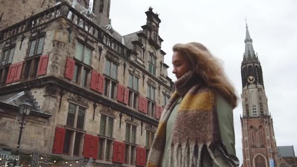 Blond blank meisje wandelen op het centrale plein van Delft Stad omringd door oude huizen — Stockvideo