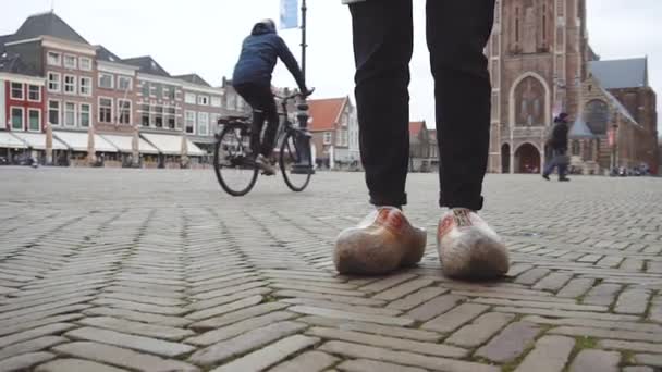 Delft, Nederland, Zuid-Holland, Europa. Meisje draagt grappige klomp houten schoenen op het marktplein in Delft. — Stockvideo