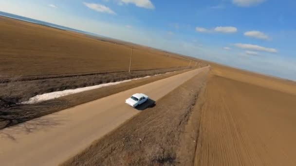 Fpv drone esporte com câmera de ação segue Old Soviet Car Volga 24 no Lonely Road Between Brown Fields. Fpv Racing drone primeira pessoa visão perseguição cinematográfica. — Vídeo de Stock