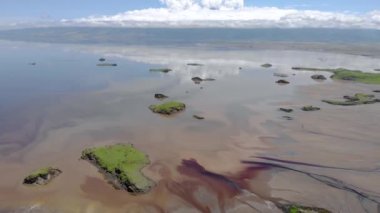 Kenya ve Tanzanya arasındaki Büyük Yarık Vadisi 'ndeki Natron Gölü' ndeki adalarda Aerial Flyby manzarası. Kurak mevsimde göl gazozla kaplıdır ve suda yüzen kuşları ve büyük sürüleriyle ünlüdür.
