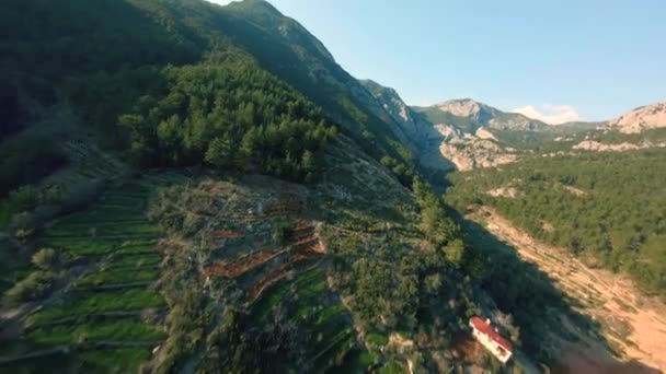 Rychlý filmový ponor v krásné horské vesnici nad kopci s terasami osvětlenými večerním sluncem při západu slunce v tureckém Pamfylském kraji. Aerial freestyle aerobatic View Shot on FPV racing — Stock video