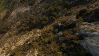 FPV insansız hava aracı atışı. Kayalık dağda, ormanla kaplı mağaralarla birlikte FPV insansız hava aracı uçuşu. Sonra da dağdan iniyor. Manavgat, Türkiye.