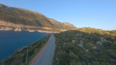 FPV Drone Shot Over the road is along the coast yarımada Kas town on beautiful cove, cazibeli doğa ve dağlar on Antalya, Türkiye. Hava görünümü.