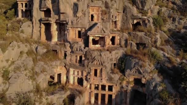 Antiguas tumbas talladas en el acantilado de roca en Demre. Aerial Drone Shot of ancient greek rock cut lykian empire anfiteatro y tumbas en Myra, Demre, Turquía — Vídeo de stock