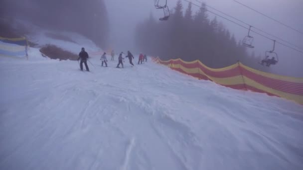 Bukovel, Ukrajna - December 2020: POV Ereszkedjen le a snowboard, ködös terület nagy magasságban Ski Resort. Ukrán síközpont szezonon kívül, Ember alkotta hó, alacsony láthatóság. — Stock videók