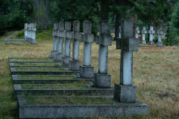 Un primer plano de una vieja cruz es uno de los muchos en la fila de cruces históricas en medio de un cementerio de guerra con una pequeña luz de vigilia de vidrio o vela votiva de pie en uno de los monumentos en Ucrania —  Fotos de Stock