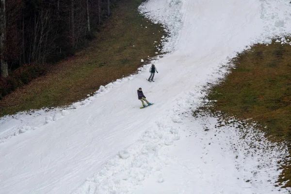 Zwei Snowboarder fahren auf künstlich verschneiten Hängen von oben — Stockfoto