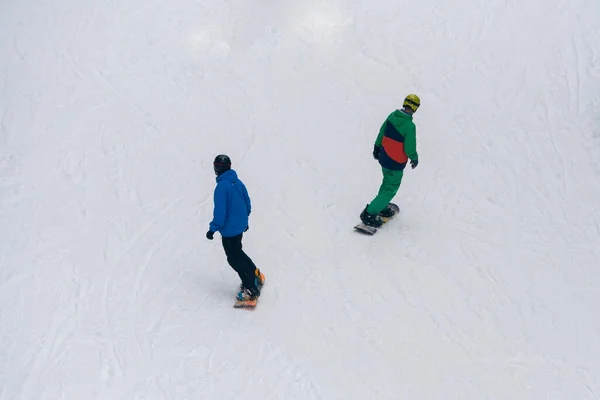 Deux snowboarders chevauchant sur la pente blanche couverte de neige vue de dessus — Photo