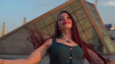 Yeşil Akşamlı Kokteylli Tekerlekli Sandalyedeki Neşeli Kız Şehir Ortamında Günbatımının tadını çıkarıyor