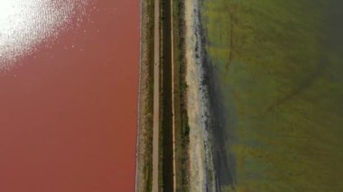 Asfalt yollu bir barajın havadan insansız hava aracı görüntüsü. Su rengi farklı olan gözlüklüler arasında. Pembe Göl ve Yeşil veya Mavi Göl Ukrayna 'da bir yol kenarında. Sivash Gölü