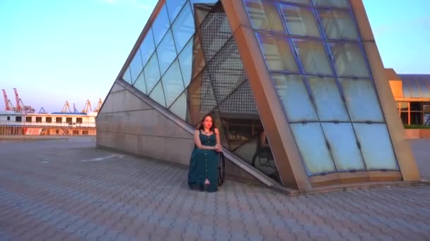 Glada söt flicka i rullstol i Green Evening Cocktail Dress poserar i stadsmiljön — Stockvideo