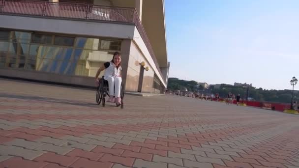 Parallax Gimbal Fly Around Slow Motion Shot eines jungen kaukasischen behinderten Mädchens im Rollstuhl in lässigem Outfit läuft am Broadway im Seehafen in Odessa — Stockvideo