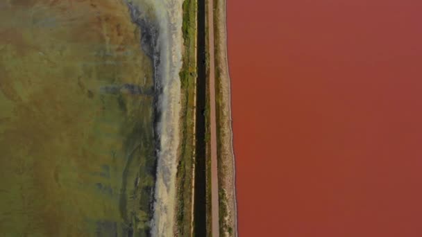 空中ドローン水の異なる色の河口の間のアスファルト道路とダムのショット。ウクライナの道路脇のピンク湖と緑や青の湖。シバシュ湖 — ストック動画