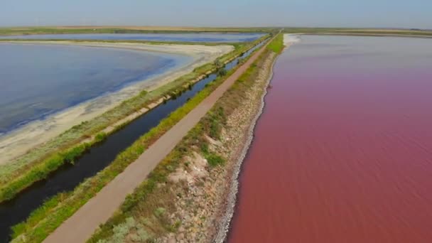 Aerial Drone Shot egy gát aszfalt Road között torkolatok különböző színű víz. Rózsaszín tó és zöld vagy kék tó félre egy út Ukrajnában. Sivash-tó — Stock videók